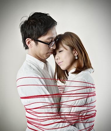 Couple hugging red thread is wound around